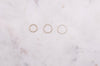 A trio of gold rings in three different thicknesses displayed on a marble board.
